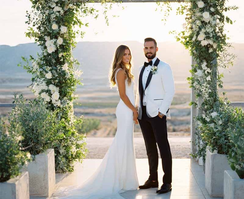 Braut und Bräutigam unter blumengeschmücktem Torbogen mit weitem Ausblick – elegante Hochzeitsfotografie in Kassel – den der schönste Tag
