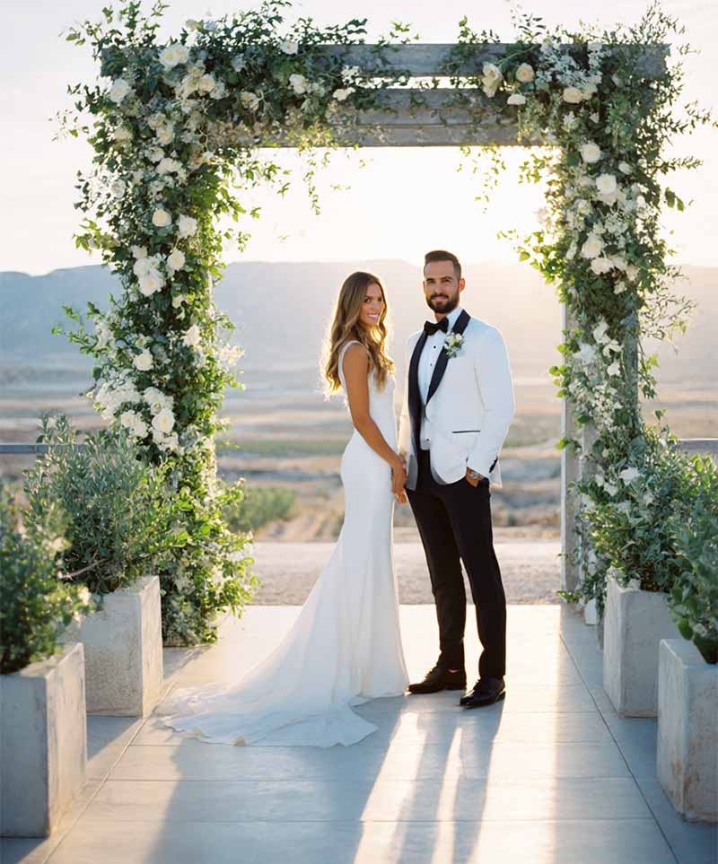 Braut und Bräutigam unter blumengeschmücktem Torbogen mit weitem Ausblick – elegante Hochzeitsfotografie in Kassel – den der schönste Tag